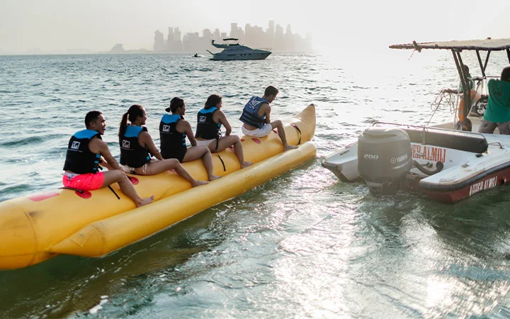 Tourists enjoying banana boat ride during Dhow Cruise & Water Sports Package in Doha