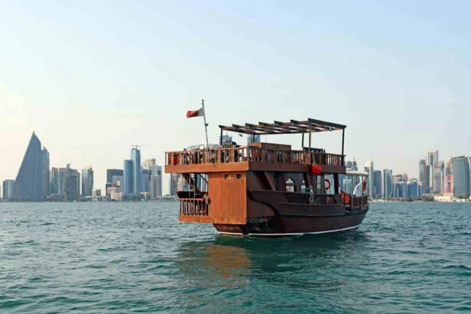 Traditional dhow boat sailing during Doha Scenic Cruise with city skyline