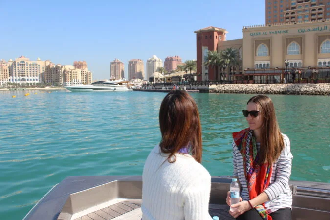Tourists enjoying Doha Scenic Cruise with Pearl Qatar skyline in view
