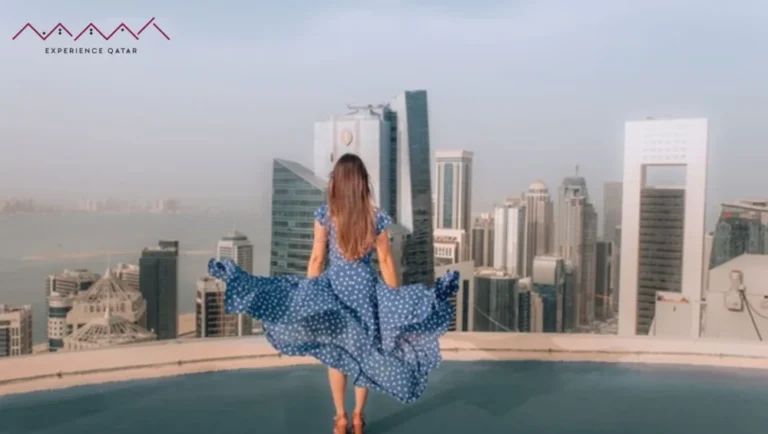 A woman in a blue dress stands on a rooftop, overlooking a city skyline with modern skyscrapers and water below—a perfect scene for female travelers seeking inspiration under the clear sky.