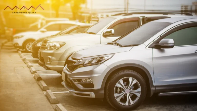 A row of parked silver and white SUVs and cars in a sunlit outdoor parking lot, highlighting Experience Qatar’s premium transportation services, with the Experience Qatar logo in the top left corner.