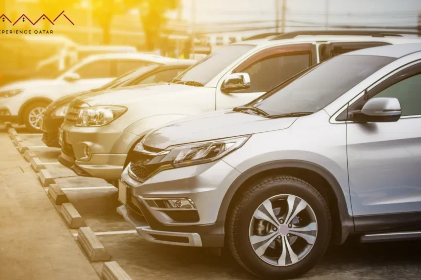 A row of parked silver and white SUVs and cars in a sunlit outdoor parking lot, highlighting Experience Qatar’s premium transportation services, with the Experience Qatar logo in the top left corner.