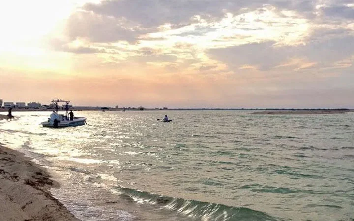 Serene sunset over Al Maroona Beach Qatar with fishing boats near the shore