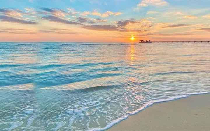 Golden sunset reflecting on the clear blue waters of Al Maroona Beach in Qatar