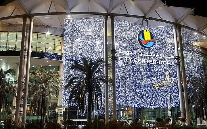 City Center Mall Doha exterior with glowing night lights in West Bay