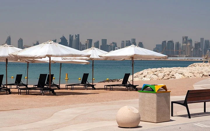 Scenic Doha skyline seen from 974 Beach Qatar with umbrellas on the sand