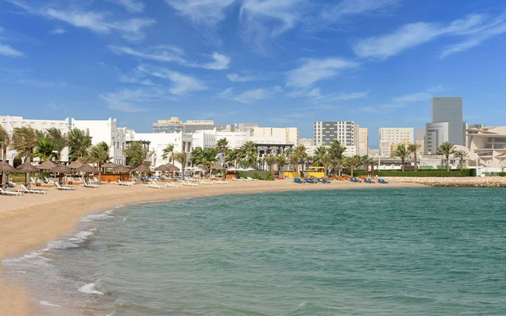 Al Sharq Beach with palm trees and nearby luxury resorts in Doha Qatar