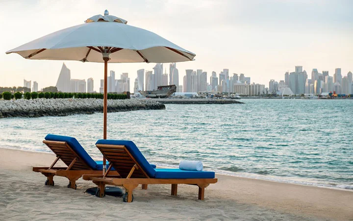 Sun loungers at Al Sharq Beach Doha with city skyline in the background
