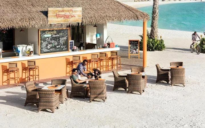 Guests enjoying food and drinks at the outdoor café on Banana Island Beach Doha