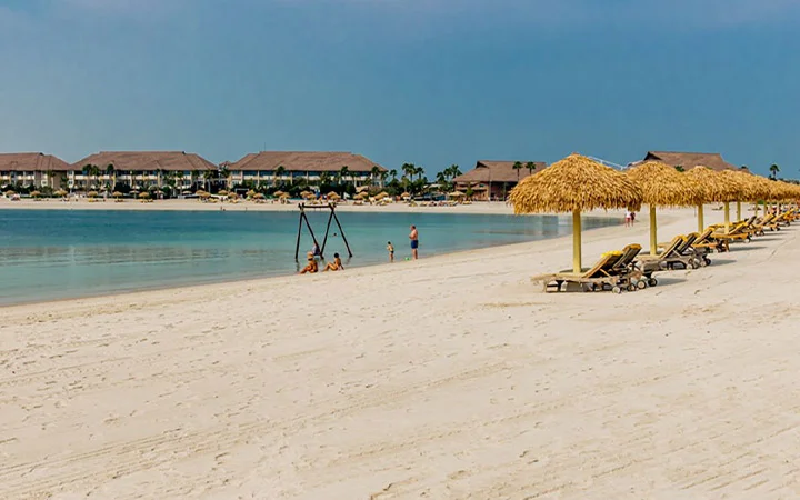 Relaxing beachfront view with straw umbrellas and sun loungers at Banana Island Beach Doha