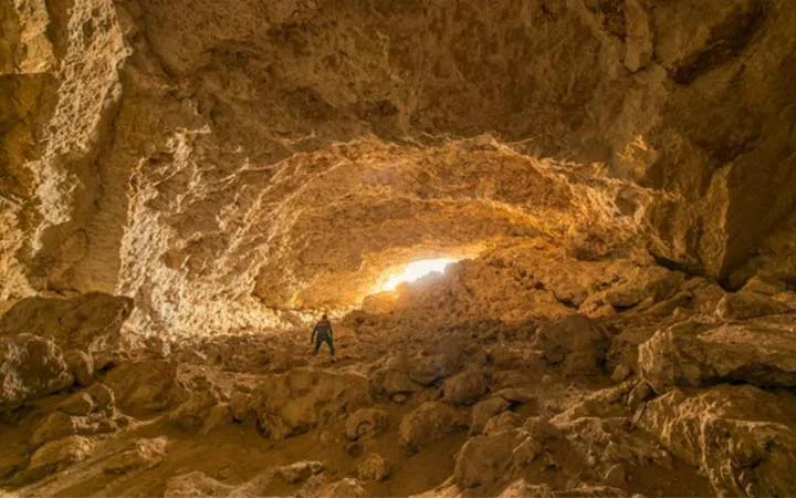 Natural rock entrance of Dahl Misfar Cave in Qatar showing sunlight and cave interior