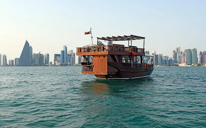 Wooden dhow sailing on Doha waters with city skyline in background