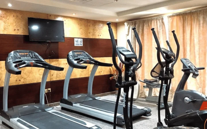 A gym room at this Tourist Hotel offers two treadmills, two elliptical machines, and a stationary bike. Enjoy workouts during your 3-star stay while watching the wall-mounted TV; large curtains cover the windows in the background.