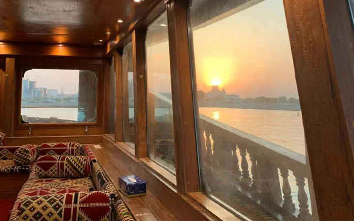 Comfortable dhow interior with traditional seating and sunset window views