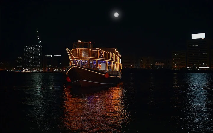Illuminated dhow boat glowing at night during Doha sunset cruise