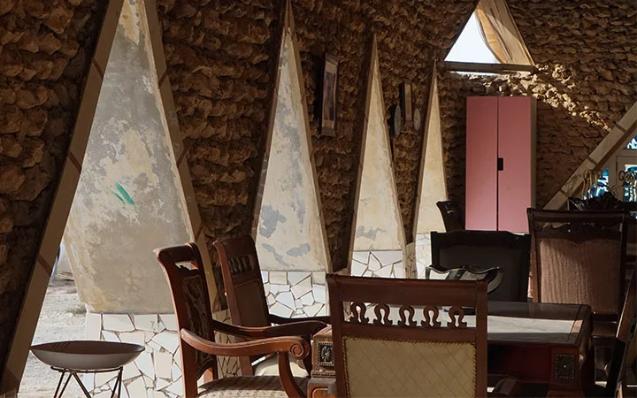 Traditional stone wall seating area with wooden chairs at Ain Mohamed Village Qatar