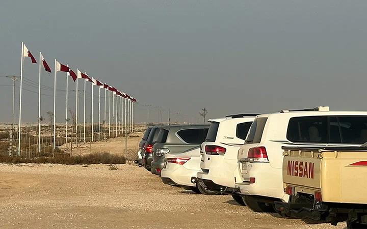 Parking lot with cars and Qatar flags at Ain Mohamed Village