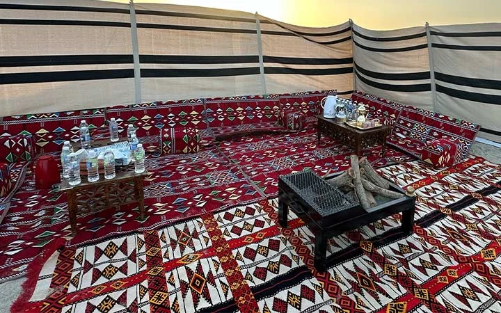 Indoor majlis setup with red carpets at Ain Mohamed Village Qatar